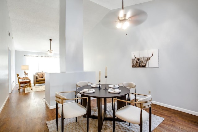 dining area with dark wood-type flooring, ceiling fan, and a textured ceiling