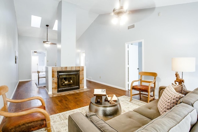 living room with high vaulted ceiling, dark hardwood / wood-style floors, ceiling fan, and a skylight