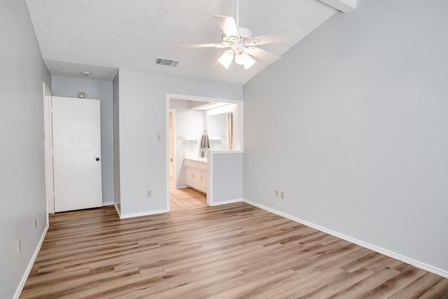 unfurnished bedroom featuring ceiling fan, lofted ceiling, light hardwood / wood-style floors, and ensuite bath