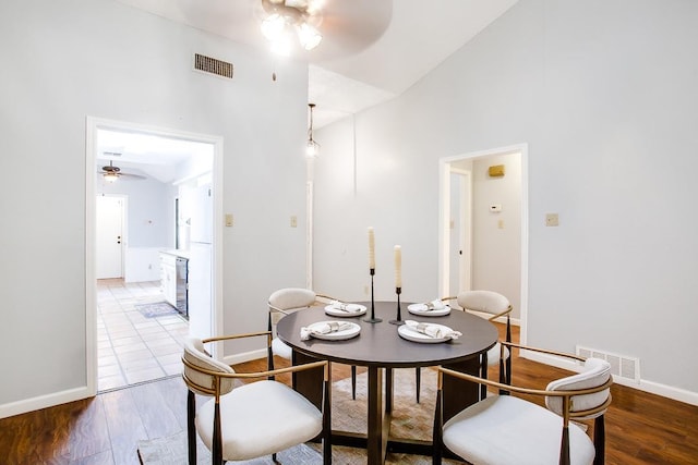 dining space with ceiling fan, wood-type flooring, and vaulted ceiling