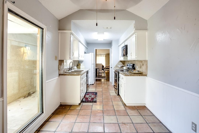 kitchen with lofted ceiling, sink, white cabinets, light tile patterned flooring, and stainless steel range with electric cooktop