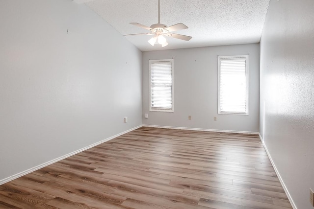 unfurnished room featuring ceiling fan, a healthy amount of sunlight, a textured ceiling, and light wood-type flooring