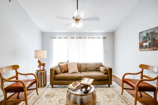 living room with a textured ceiling, ceiling fan, and light wood-type flooring