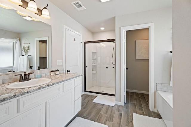 bathroom with vanity and shower with separate bathtub