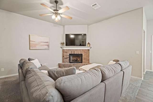 living room with ceiling fan and a brick fireplace