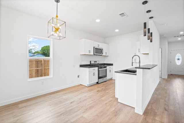 kitchen featuring pendant lighting, sink, white cabinetry, stainless steel appliances, and light wood-type flooring