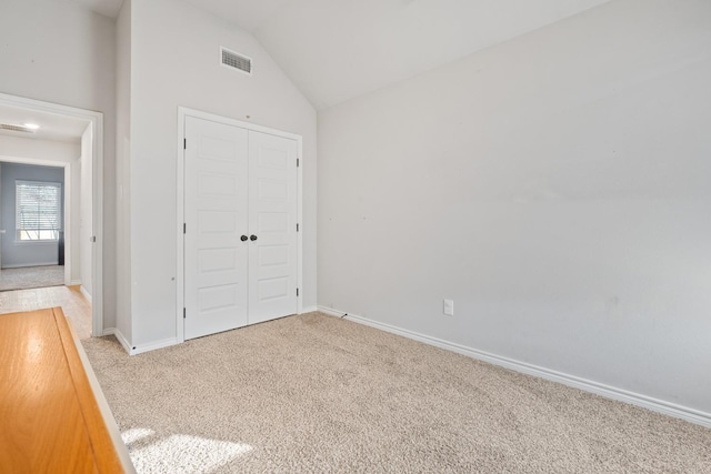 unfurnished bedroom featuring lofted ceiling, light colored carpet, and a closet