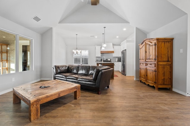 living room with hardwood / wood-style floors, a notable chandelier, and lofted ceiling with beams