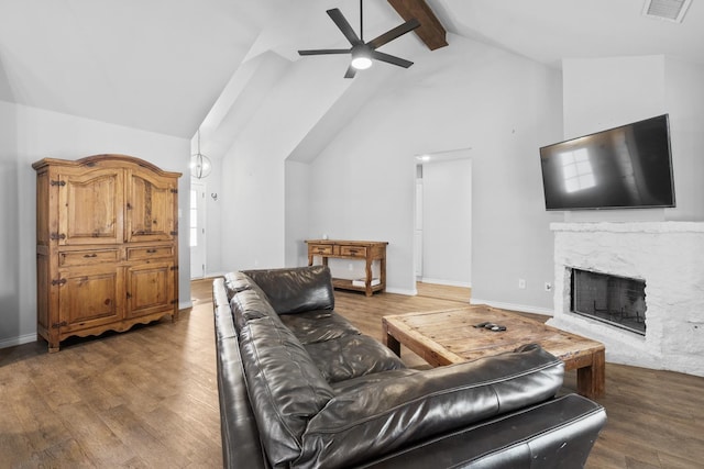 living room with ceiling fan, vaulted ceiling with beams, dark wood-type flooring, and a fireplace