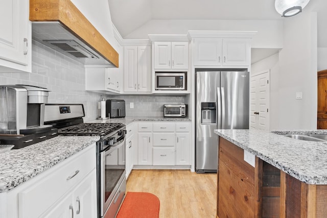 kitchen with appliances with stainless steel finishes, custom range hood, white cabinets, and decorative backsplash