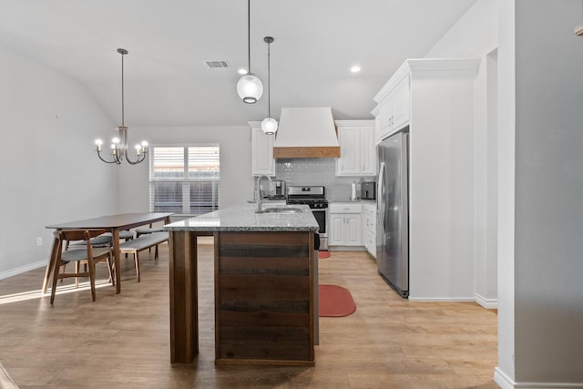 kitchen featuring premium range hood, pendant lighting, stainless steel appliances, a kitchen island with sink, and white cabinets