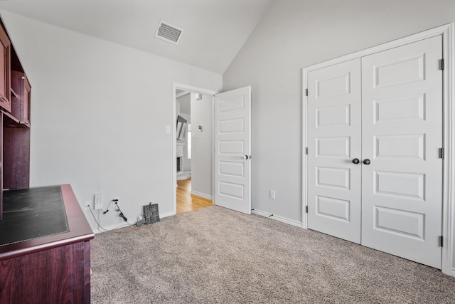 unfurnished bedroom with lofted ceiling, light carpet, and a closet