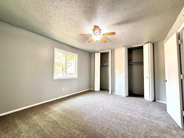 unfurnished bedroom with ceiling fan, two closets, a textured ceiling, and carpet