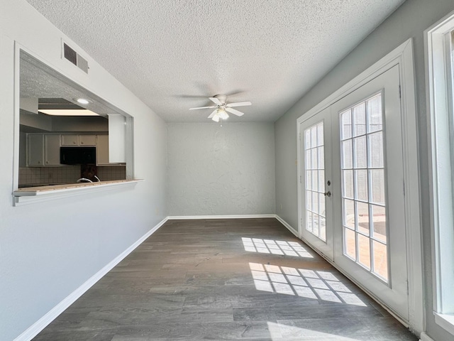 empty room featuring dark hardwood / wood-style flooring, plenty of natural light, french doors, and a textured ceiling