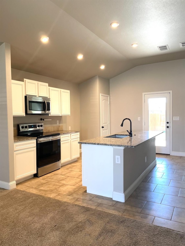 kitchen with sink, appliances with stainless steel finishes, white cabinetry, light stone countertops, and a center island with sink