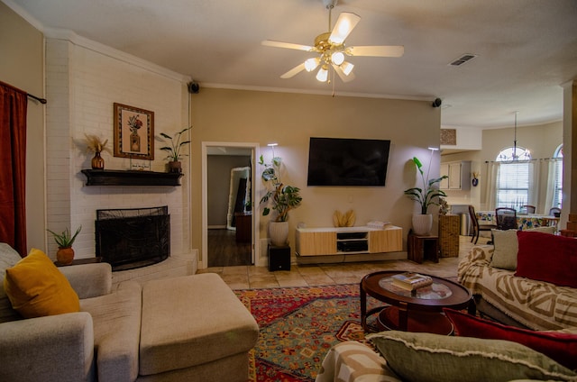 living room featuring a fireplace, light tile patterned floors, crown molding, a ceiling fan, and visible vents