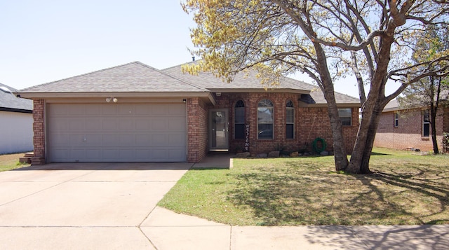 ranch-style home featuring brick siding, a garage, roof with shingles, a front yard, and concrete driveway