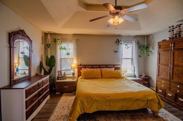 bedroom featuring a textured ceiling, multiple windows, ceiling fan, and dark wood finished floors