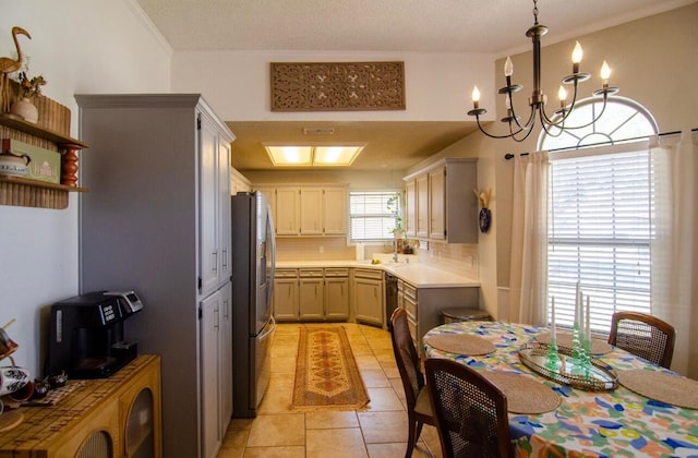kitchen featuring light tile patterned floors, crown molding, light countertops, a notable chandelier, and stainless steel fridge