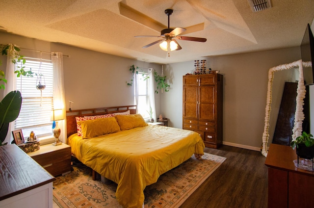 bedroom featuring wood finished floors, baseboards, visible vents, a ceiling fan, and a textured ceiling