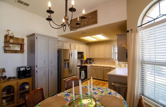 kitchen with stainless steel fridge, range, black microwave, visible vents, and light countertops