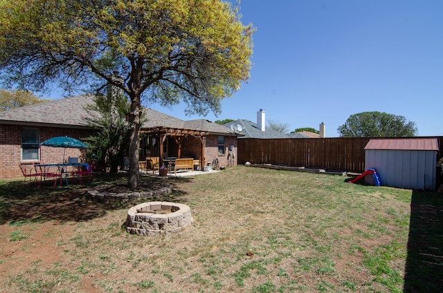 view of yard with an outdoor structure, a patio area, a storage shed, an outdoor fire pit, and fence