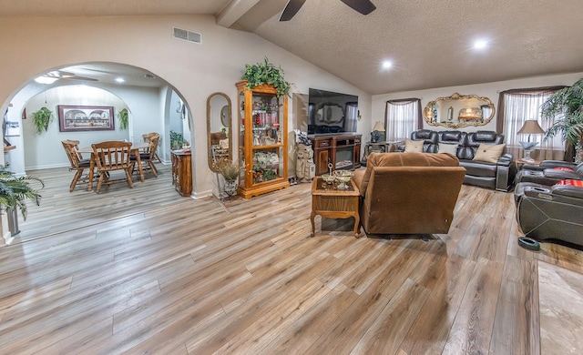 living room featuring vaulted ceiling with beams, light hardwood / wood-style floors, a textured ceiling, and ceiling fan