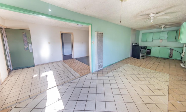 kitchen with light tile patterned floors, ceiling fan, stainless steel gas stove, a textured ceiling, and green cabinetry