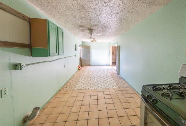 kitchen with light tile patterned floors, stainless steel gas range, ceiling fan, a textured ceiling, and green cabinetry