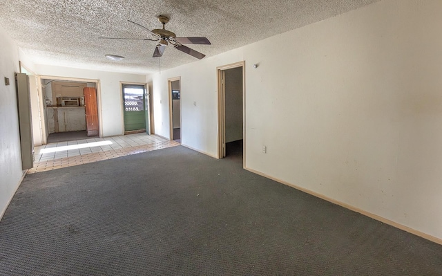 carpeted spare room featuring a textured ceiling and ceiling fan