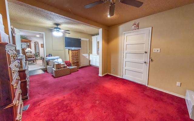 carpeted living room featuring ceiling fan and a textured ceiling