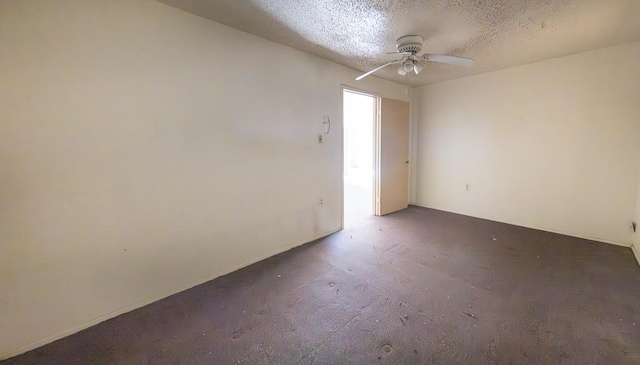 spare room with ceiling fan, dark carpet, and a textured ceiling