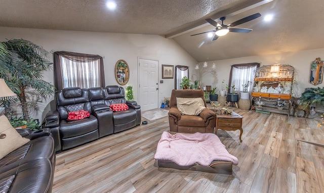 living room with vaulted ceiling with beams, ceiling fan, a textured ceiling, and light wood-type flooring