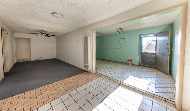 tiled empty room featuring ceiling fan and a textured ceiling