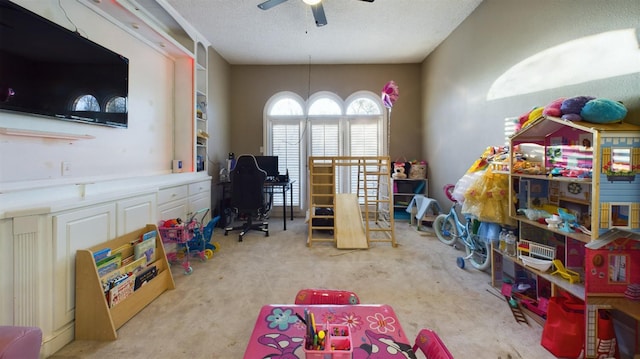 playroom with ceiling fan, light colored carpet, and a textured ceiling