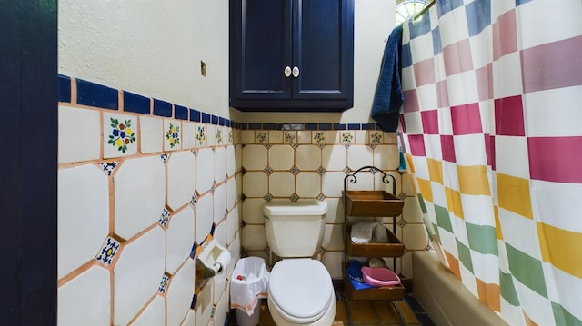 bathroom featuring tile walls, shower / tub combo, and toilet