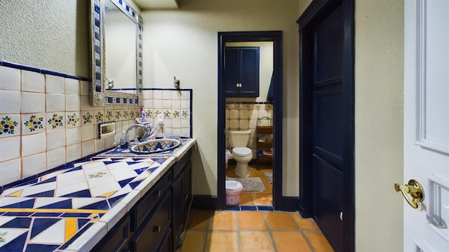 bathroom featuring vanity, decorative backsplash, tile patterned floors, and toilet