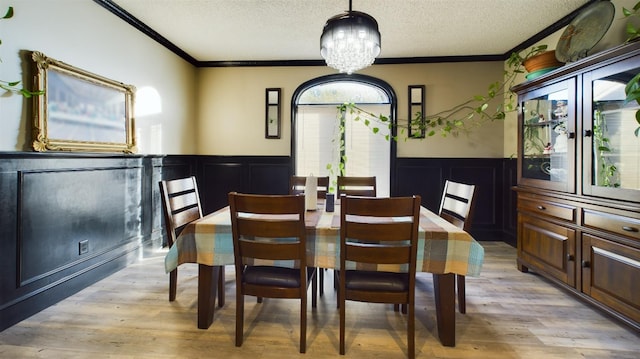 dining area with crown molding, an inviting chandelier, a textured ceiling, and light hardwood / wood-style flooring