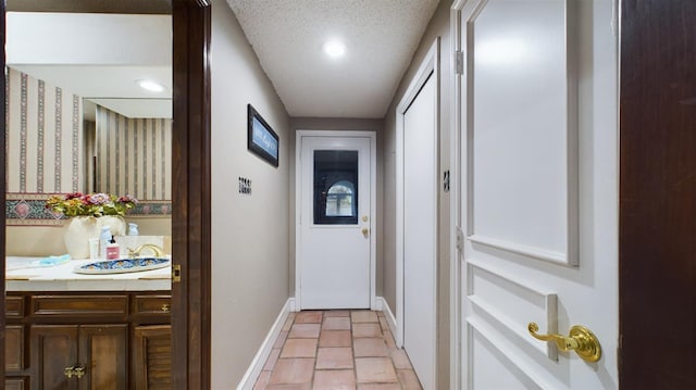 hall featuring a textured ceiling and light tile patterned flooring