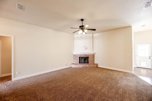 unfurnished living room featuring ceiling fan, carpet flooring, and a brick fireplace