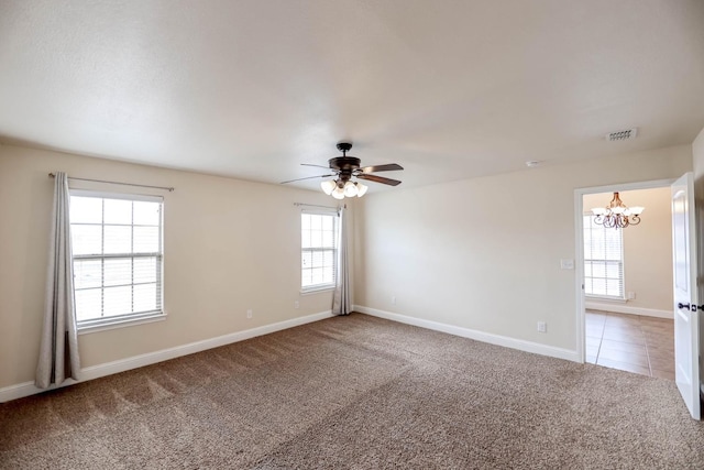 carpeted spare room with ceiling fan with notable chandelier