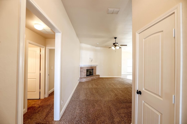 unfurnished living room with dark carpet, a fireplace, and ceiling fan