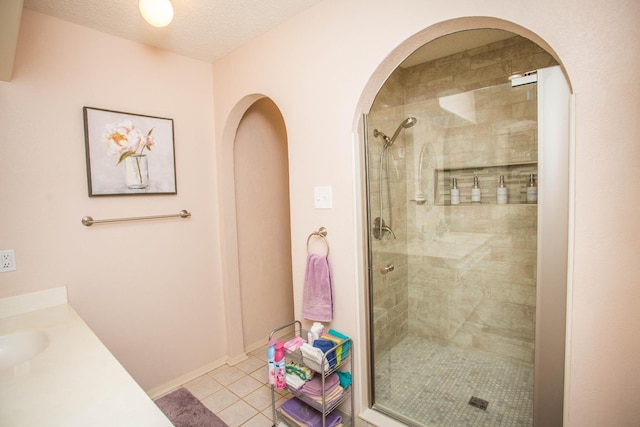 bathroom featuring tile patterned flooring, vanity, a textured ceiling, and walk in shower