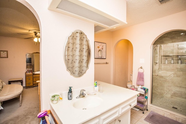 bathroom featuring tile patterned flooring, an enclosed shower, ceiling fan, toilet, and a textured ceiling