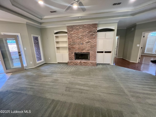 9802 Toledo Ave, Lubbock, TX 79424 - unfurnished living room featuring a raised ceiling, carpet floors, ornamental molding, ceiling fan, and a fireplace