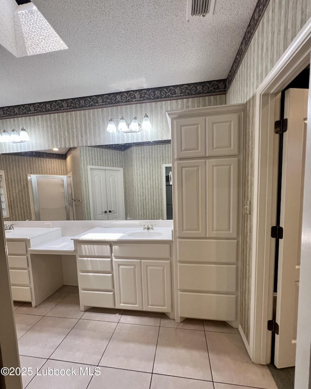 9802 Toledo Ave, Lubbock, TX 79424 - bathroom featuring wallpapered walls, tile patterned floors, vanity, a textured ceiling, and a skylight