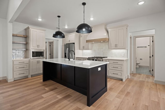 kitchen featuring decorative light fixtures, appliances with stainless steel finishes, custom range hood, decorative backsplash, and white cabinets