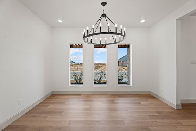 unfurnished dining area with light hardwood / wood-style flooring and a notable chandelier