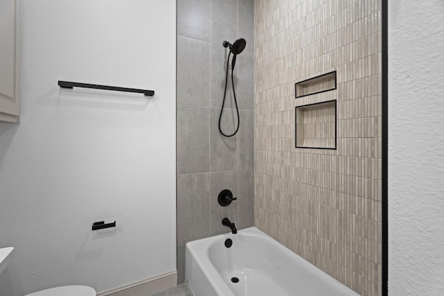 bathroom featuring tiled shower / bath combo and toilet