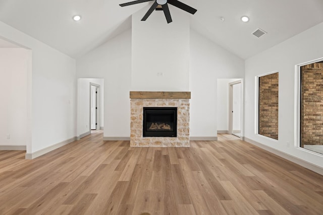 unfurnished living room featuring a tiled fireplace, high vaulted ceiling, light hardwood / wood-style floors, and ceiling fan